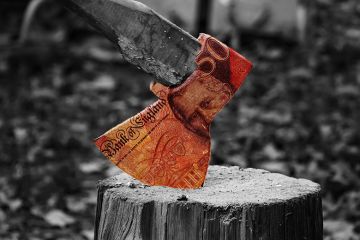 Axe on a block of wood with £50 banknote on the axe head. To illustrate the cost of severance pay.