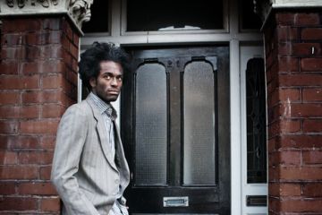 A black man waits in a doorway illustrating opinion article about equity in higher education