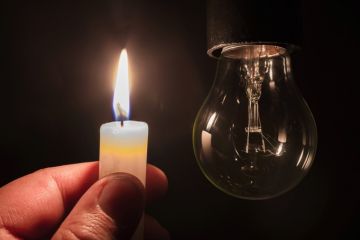 A lit candle and an unlit lightbulb A lit candle and an unlit lightbulb
