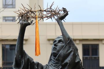 Catholic statue of Catherine of Sienna holding a crown of thorns, St. Patrick's Cathedral, East Melbourne, Australia. With a mortarboard tassel added to illustrate the double act of being Catholic and being a university.