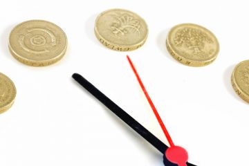 Clock hands and pound coins counting time