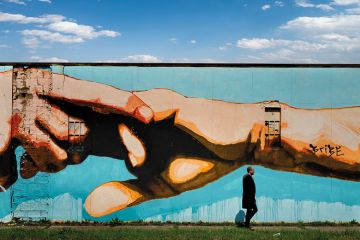 Man walking past mural of clasped hands