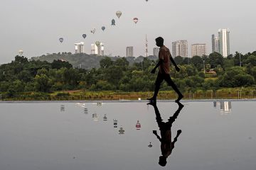 Man reflected in water in Asian city on the cover of 24 June 2021 issue of Times Higher Education magazine