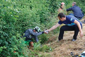 Two men helping cyclists who fell off their bikes