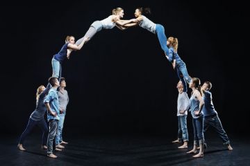 Dancers on stage forming human bridge