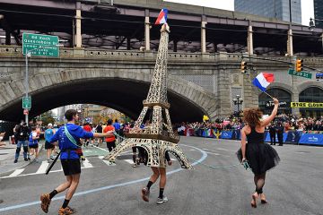 A runner carries a model of the Eiffel Tower during the New York City Marathon in New York, USA. To illustrate that European governments and institutions are launching schemes to attract US talent.