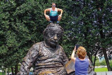 Man squatting on Albert Einstein memorial statue Man squatting on Albert Einstein memorial statue