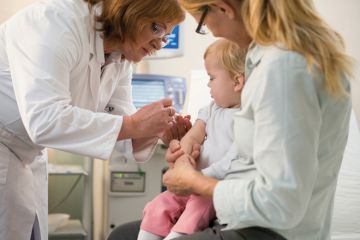 Female doctor administering vaccine to small child Female doctor administering vaccine to small child
