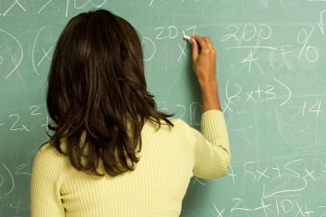 Female lecturer writing on classroom blackboard Female lecturer writing on classroom blackboard