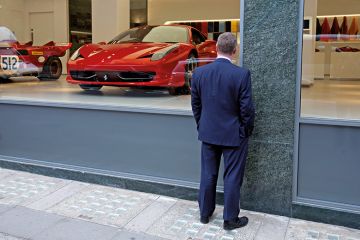 Man window shopping at Ferrari showroom Man window shopping at Ferrari showroom