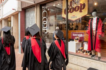 Harvard University students Harvard University students wearing graduation gowns walk past a bookstore near the Harvard University campus in Cambridge, Massachusetts, US