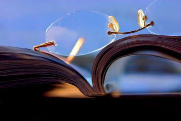 Glasses lying on top of a journal Glasses lying on top of a journal