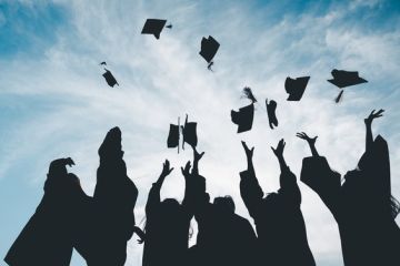 Graduates throw their caps into the air, symbolising the graduate premium