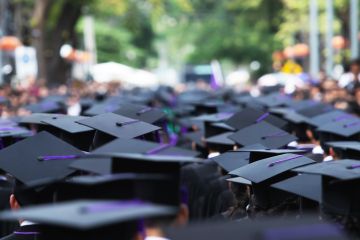A line of graduates proceeding into a blur, illustrating uncertain prospects