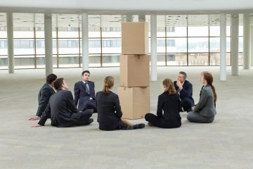 Group of businesspeople sat around pile of cardboard boxes