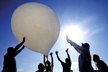 Group of people push balloon into the air Group of people push balloon into the air