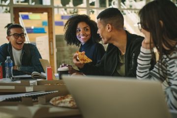 Group of students eating pizza at college canteen