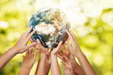 Many hands holding up the Earth, symbolising collaboration to meet the SDGs