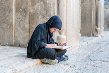 An Iranian student sits on the ground, illustrating inequliaty in university entrance