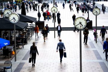 Business people walking in Canary Wharf by the iconic clock installation on Reuters plaza, London's financial district. Business people walking in Canary Wharf by the iconic clock installation on Reuters plaza, London's financial district.