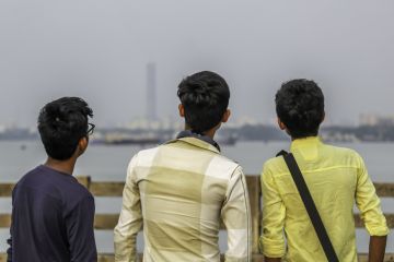 Group of three friends having fun at sunset time.