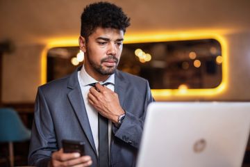 A candidate adjusts his tie before a job interview. Online interviews add an extra layer of difficulty to an already stressful situation.