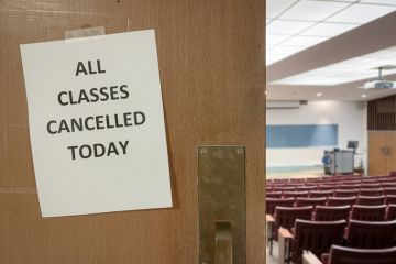 Close-Up of a Notice on a Door to an Empty Classroom that Reads "All Classes Cancelled Today"