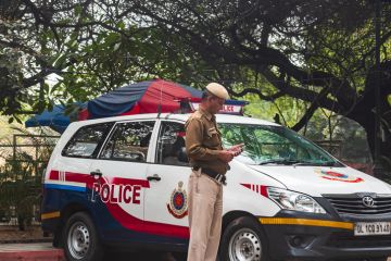 Delhi, India: A policeman in front of a red and white mini van patrolling the state border of the Delhi, state. Delhi, India: A policeman in front of a red and white mini van patrolling the state border of the Delhi, state.