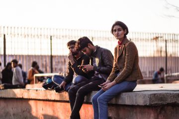 Group of students sitting in a campus Group of young male and female students sitting inside the university campus of Jamia Millia Islamia entrance door.