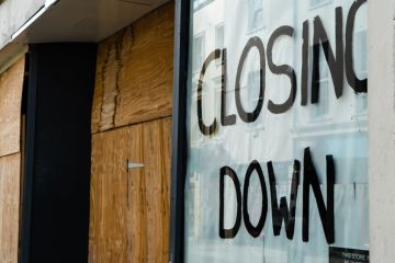 Closing down sign in a boarded-up shop window Closing down sign in a boarded-up shop window