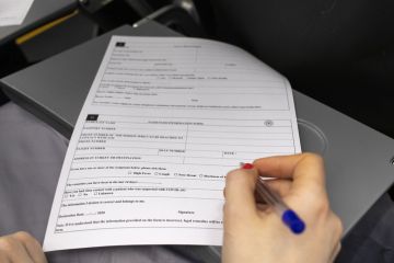 A woman on board a plane fills out a passenger information form.