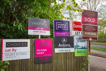 color image depicting a collection of different property for sale and sold signs in a residential district in the town of Crawley, UK.