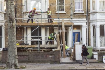 Four workers collaborate to build a scaffold during the refurbishment of a residential premises in London.