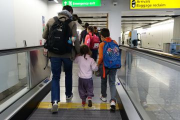 Air travellers walk on a moving walkway or travellator through Heathrow Airport.
