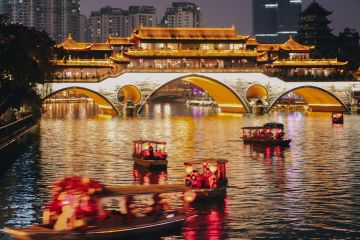  Stream of little tour boats on the Jinjiang River at night, passing the Anshun Bridge, in Chengdu, Sichuan, China