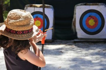 Young girl archer aiming to target.
