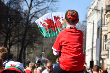Young girl on father’s shoulders waving a Welsh flag Young girl on father’s shoulders waving a Welsh flag.