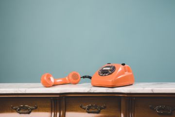 View of an old retro telephone with the receiver off the hook on a table
