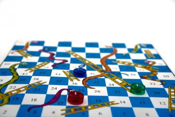 Snakes and ladders board with one counter at the top of a snake, another at the foot of a ladder Snakes and ladders board with one counter at the top of a snake, another at the foot of a ladder