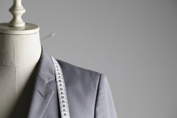 Suit jacket on tailor's mannequin with pins and tape measure