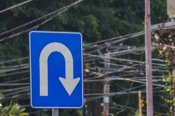 Right U turn sign on blue colored board with cityscape backgrounds.