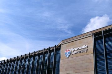 Newcastle University Kings Gate building, with university logo and lettering against sandstone wall Newcastle University Kings Gate building, with university logo and lettering against sandstone wall