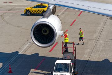 Airport technician doing maintenance work at jet engine of Edelweiss Air Airbus A340-300 HB-JMC airplane on a sunny summer day. Airport technician doing maintenance work at jet engine of Edelweiss Air Airbus A340-300 HB-JMC airplane on a sunny summer day.