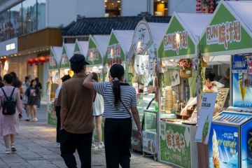 A couple walks past ice cream stalls during an evening festival in Suzhou, China.