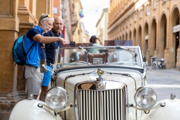 Two men admiring an MG T-Series car parked in the city centre in Bologna