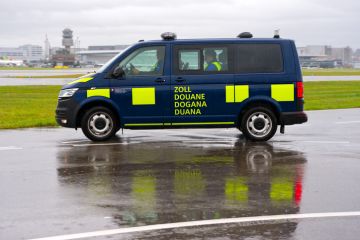 Dark blue van of Swiss customs passing at Zürich Kloten Airport on a rainy autumn day. Dark blue van of Swiss customs passing at Zürich Kloten Airport on a rainy autumn day.