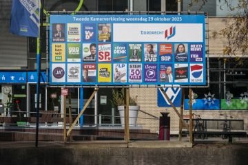 Dutch national election posters from various political parties displayed on a public board in Dordrecht