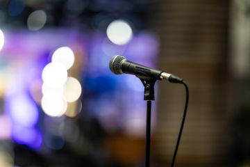 Close-up of a professional microphone on a stand with colorful stage lights blurred in the background