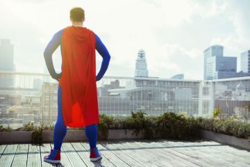 Superhero looking at view from city rooftop Superhero looking at view from city rooftop