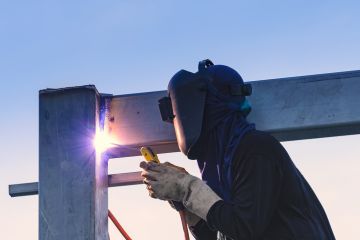 Worker welding parts of steel construction together